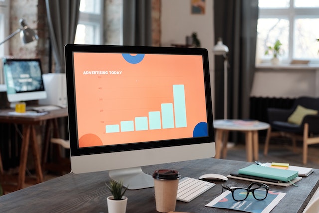 Desktop computer displaying a blue and orange advertising graph